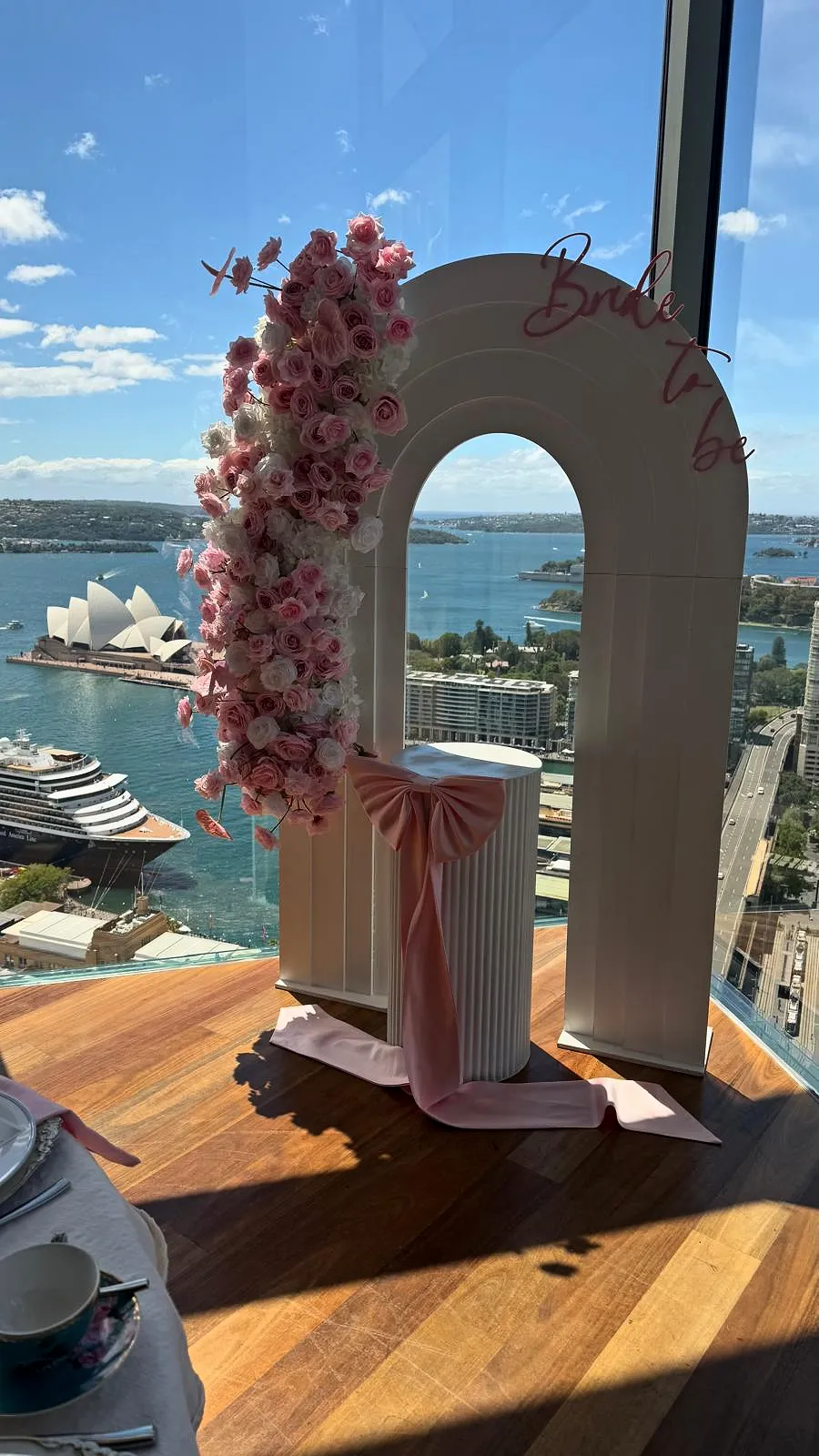 Bride-to-be arch with pink florals on a deck overlooking the Opera House and Sydney Harbour