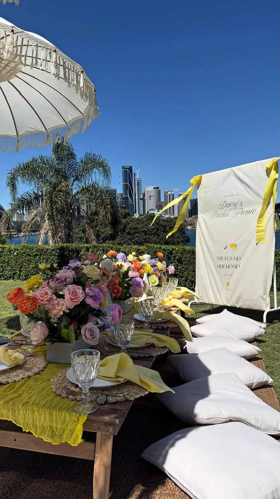 Colourful picnic with yellow runners, fresh flowers and a welcome sign, with the city skyline behind