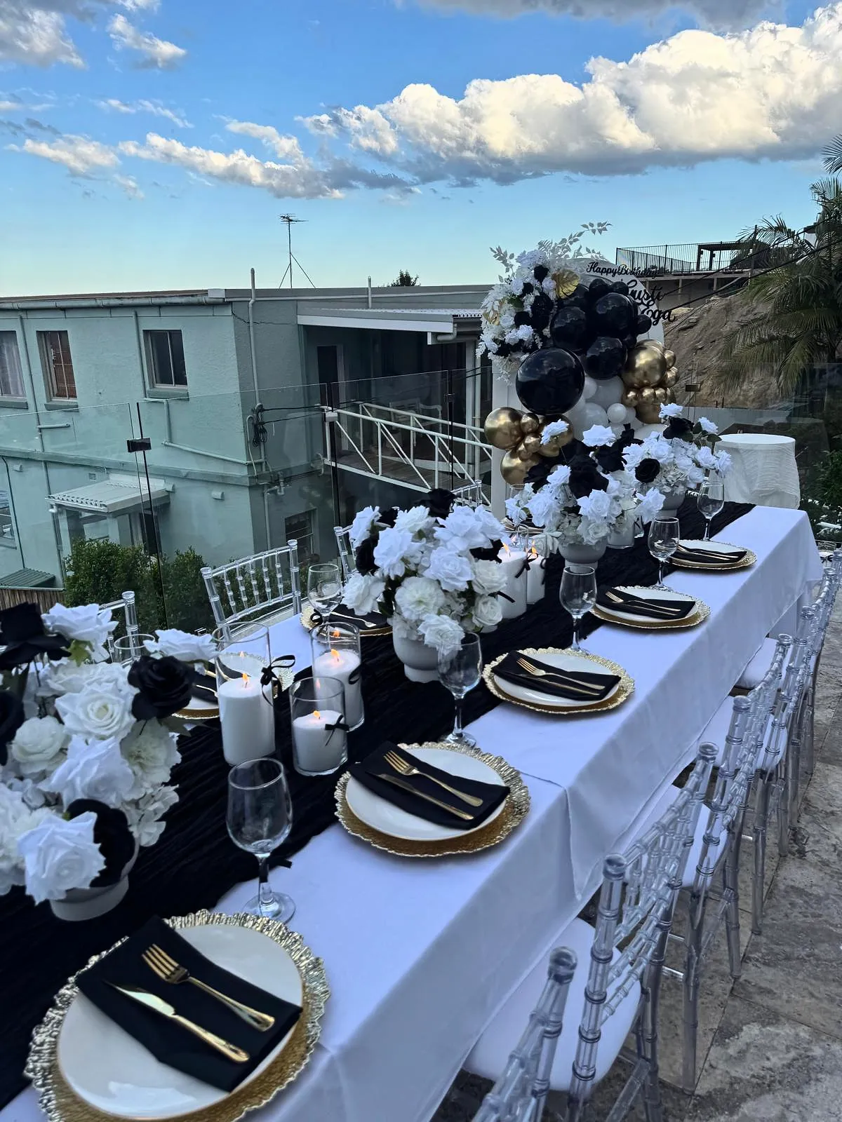 Black and white table with white florals on a balcony under a blue sky